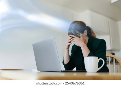 Woman stressed at work, sitting at a desk with a laptop and coffee. Stress and work pressure visible. Office setting with a stressed woman. Stressed woman working on laptop at home with copyspace. - Powered by Shutterstock