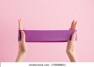 Woman stretch fitness band. Violet rubber for home exercises. Indoor and outdoor workout. Sport and healthy active lifestyle concept. Isolated on pink background - Powered by Shutterstock