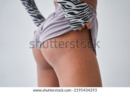 Woman with stretch marks at her buttocks standing back to the camera at the sportive clothes