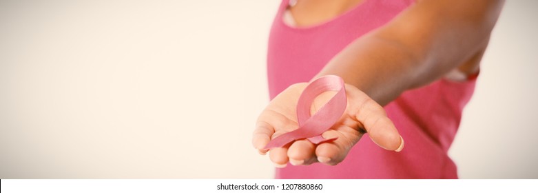 Woman stretches arm showing pink ribbon for breast cancer awareness against white background - Shutterstock ID 1207880860