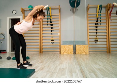 Woman stretching back with help of wooden stick 