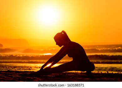 Woman stretching in beach at beautiful sunset. Fitness girl exercising and working out enjoying the quiet in nature. - Powered by Shutterstock