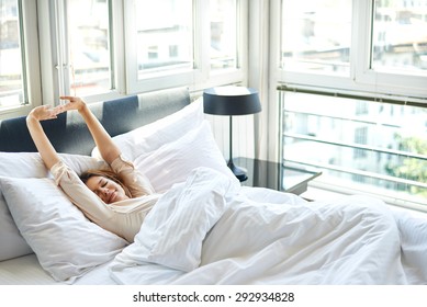 Woman stretching in bed after wake up - Shutterstock ID 292934828