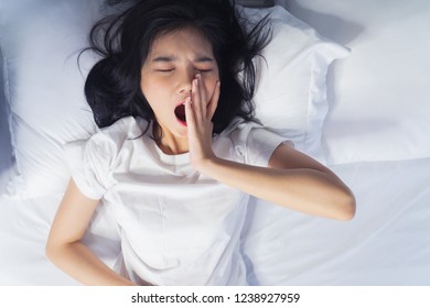 Woman stretching in bed after waking up, back view. Woman sitting near the big white window while stretching on bed after waking up with sunrise at morning, back view. - Shutterstock ID 1238927959