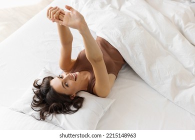 Woman stretching in bed after waking up - Powered by Shutterstock