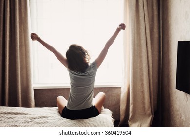 Woman Stretching In Bed After Waking Up, Back View
