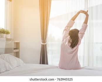 Woman stretching in bed after waking up, back view, entering a day happy and relaxed after good night sleep. Sweet dreams, good morning, new day, weekend, holidays concept - Shutterstock ID 763945525