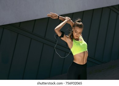 Woman Stretching Body, Doing Exercises On Street. Beautiful Athletic Girl With Fit Body In Bright Sportswear Warming Up, Doing Stretches Before Fitness Workout Outdoors. High Resolution