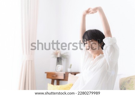 Woman stretching comfortably in her room, profile