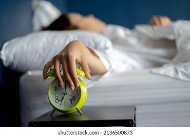 Woman stretching hand to ringing alarm willing turn it off, pressing button, woken by signal, not getting enough sleep concept. - Shutterstock ID 2136500873