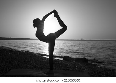 Woman stretching in yoga exercise fitness training at coastline at sunset, monochrome image - Powered by Shutterstock