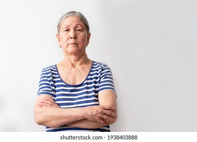 A Woman In A Striped Blue And White Dress Has Her Arms Crossed On A White Background. Close-up Face Portrait Headshot. The Concept Of Old Age, Wisdom And Joy.