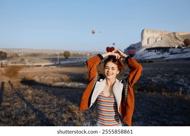 Woman in striped sweater holding apple against mountain backdrop with hot air balloons - Powered by Shutterstock