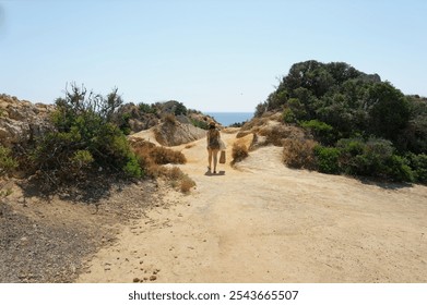 Woman strolling along a scenic coastal path towards the Atlantic at Ponta da Piedade. - Powered by Shutterstock