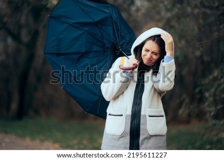 
Woman Struggling During Raining Storm Holding an Umbrella. Unhappy girl fighting windstorms outdoors in nature
