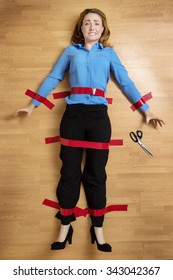 Woman Stuck To The Floor With Red Tape, Arms Out To The Sides, Scissors Just Out Of Reach