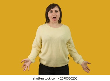 woman stuck out her tongue and spread her arms to the sides on a yellow background