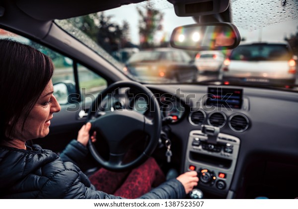 Woman stuck in a traffic jam listening radio on a\
rainy day