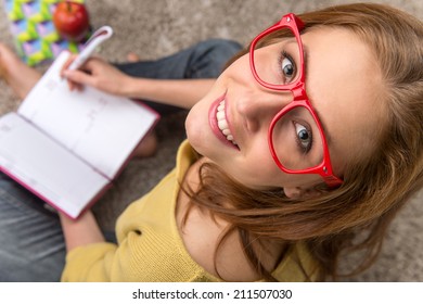 Woman student sitting thinking while studying. top view of pretty girl making note in textbook