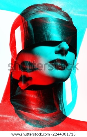 Woman studio portrait with big silver futuristic glasses or helmet covering her eyes in red and blue color split effect. Model wearing dark blouse in white studio background. Futuristic looking style