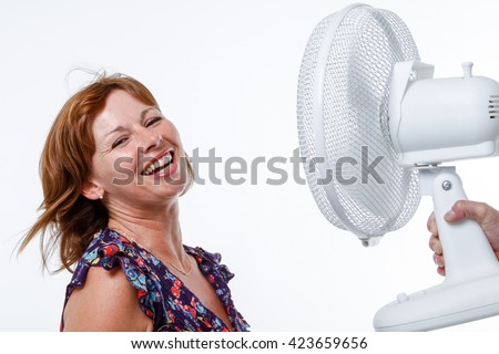 Woman in studio smiles as air from a handheld fan blows her hair