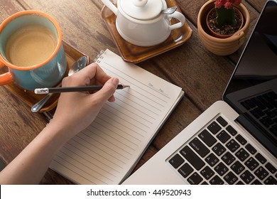 Woman Studying With Laptop And Taking Notes On A Desktop At Cafe