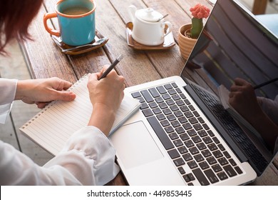 Woman Studying With Laptop And Taking Notes On A Desktop At Cafe