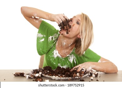 A Woman Stuffing Her Face With Chocolate Cake.  She Is Covered All Over In Frosting And Cake.