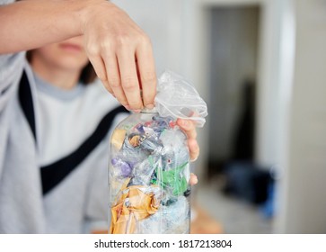 Woman stuffing soft waste plastics into a plastic bottle to make an ecobrick - Shutterstock ID 1817213804