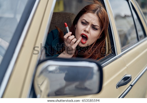 Woman\
style in car paints lips, woman driving a retro\
car