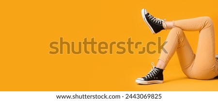 Woman in stylish gumshoes on yellow background with space for text