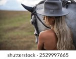 Woman in Stylish Outfit with Horse in Open Countryside.