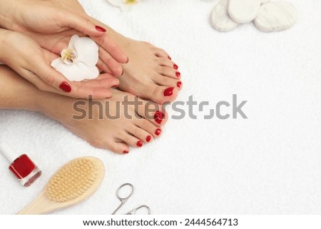 Woman with stylish red toenails after pedicure procedure and orchid flowers on white terry towel, top view. Space for text