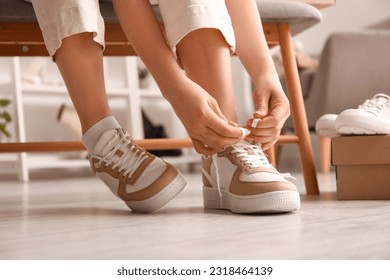 Woman in stylish sneakers tying shoe lace, closeup