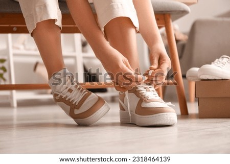 Woman in stylish sneakers tying shoe lace, closeup