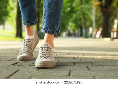 Woman in stylish sneakers walking on city street, closeup. Space for text