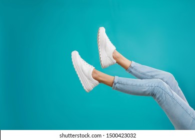 Woman in stylish sport shoes on light blue background