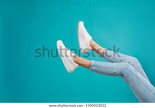 Woman in\
stylish sport shoes on light blue\
background