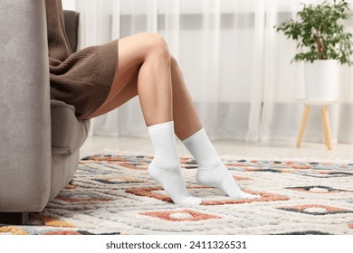 Woman in stylish white socks in armchair indoors, closeup. Space for text - Powered by Shutterstock