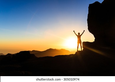 Woman successful hiking climbing silhouette in mountains, motivation and inspiration in beautiful sunset and ocean. Climber arms up outstretched on mountain top looking at inspirational landscape.