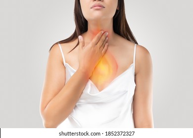 A woman suffering from acid reflux or Heartburn on gray Background