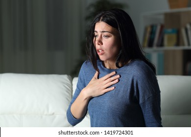 Woman suffering an anxiety attack alone in the night on a couch at home - Shutterstock ID 1419724301