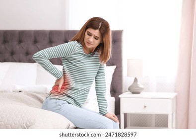 Woman suffering from back pain on bed at home - Powered by Shutterstock