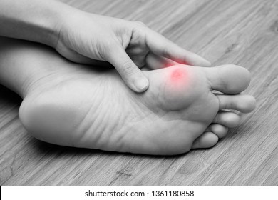 A woman suffering from corn on her foot sole. Black and white tone with red spot on her corn