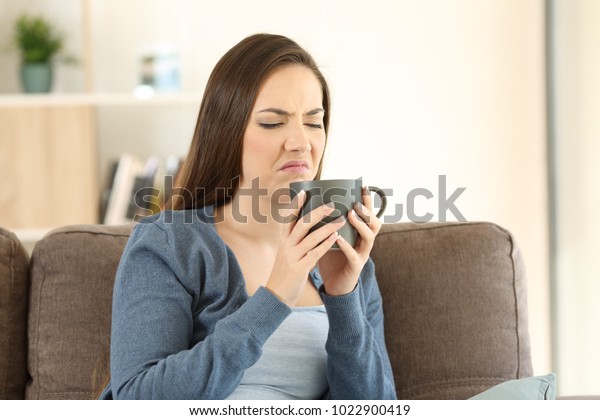 Woman suffering drink bad taste sitting on a couch
in the living room at
home