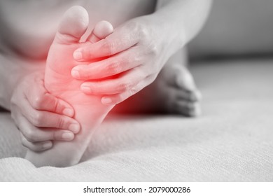 A woman suffering from feeling knee pain sitting sofa at home. hand massaging her painful knee. Health care and medical concept. - Shutterstock ID 2079000286