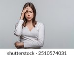 Woman suffering from headache desperate, stressed because pain and migraine. Woman touching her temples feeling stress, on gray background. Girl suffering from headache. Cold symptoms.