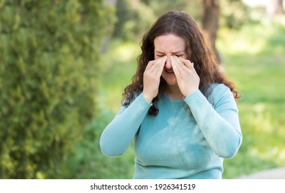 Woman suffering itching scratching eyes outdoors in a park