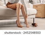 Woman suffering from leg pain after wearing high heels at home, closeup