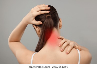 Woman suffering from neck pain on grey background, back view - Powered by Shutterstock